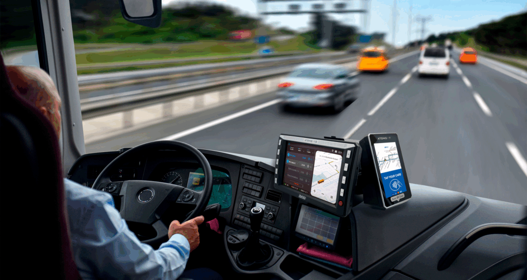 bus driver operating an atomo 10 ets all-in-one console with touchscreen display and mobile device while driving on the highway