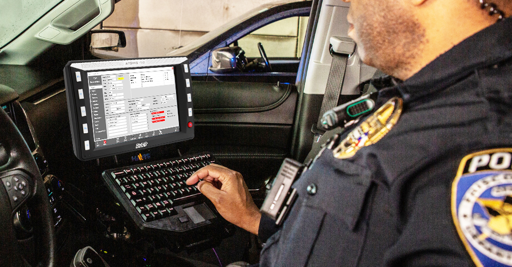law enforcement officer operating a digitax atomo 10 mobile data terminal with keyboard in a patrol car